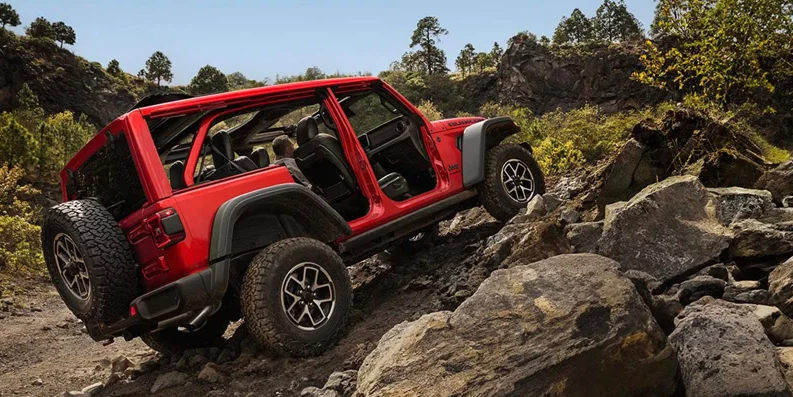 A 2026 Jeep Wrangler off-roading up a rocky hill.